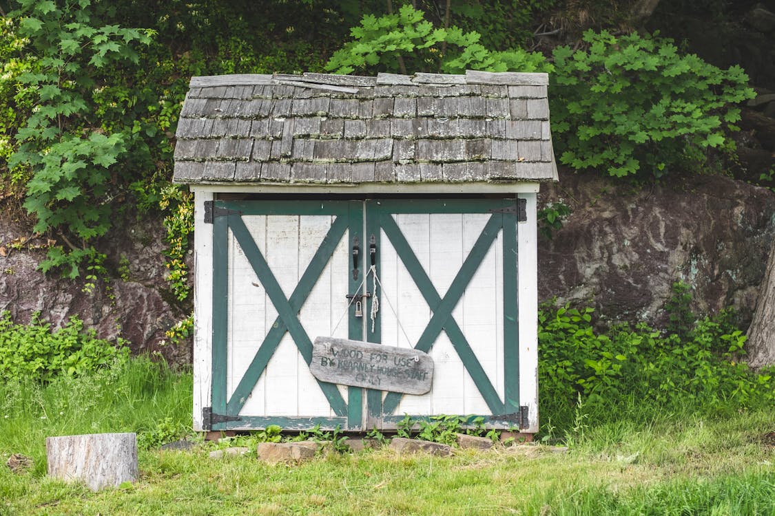 Rustic wooden shed with stone foundation surrounded by greenery
